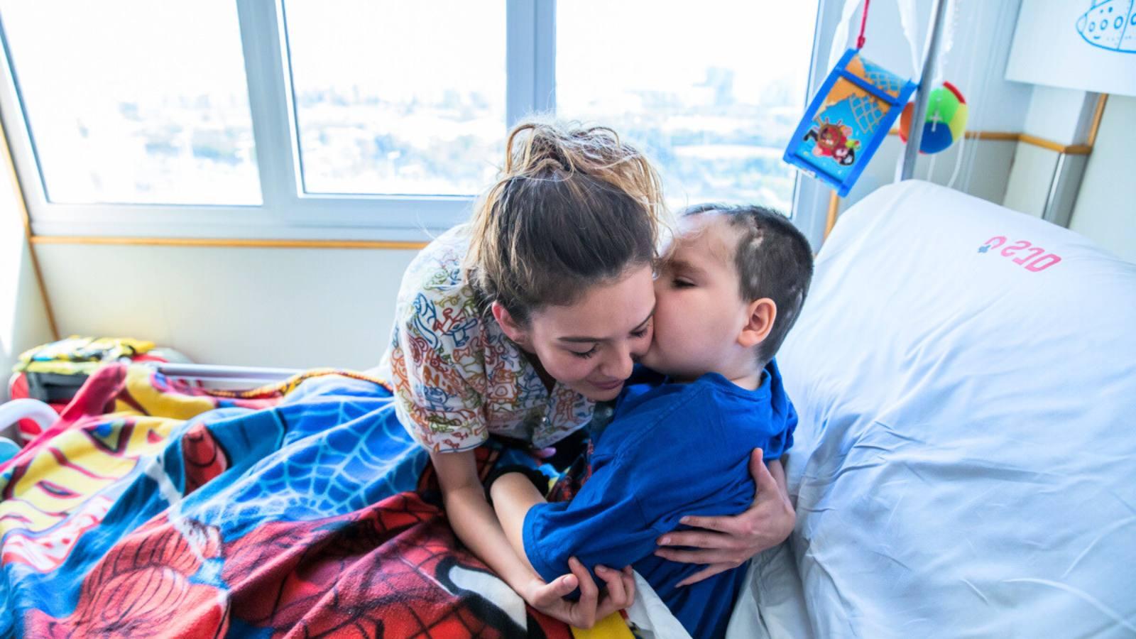 A patient of the SJD Barcelona Children's Hospital kisses the nurse who attends him