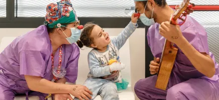 Paciente sonriendo y tocando la nariz a un payaso de Hospital