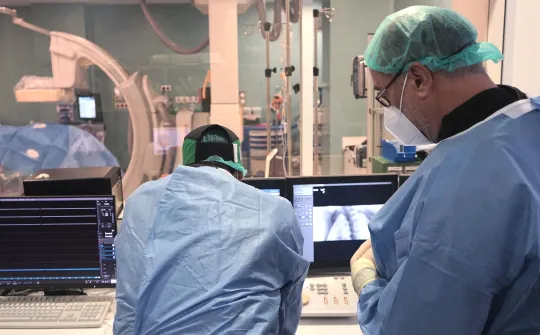 Два хирурга просматривают результаты визуализационного исследования в операционной. Два хирурга просматривают результаты визуализационного исследования в операционной.