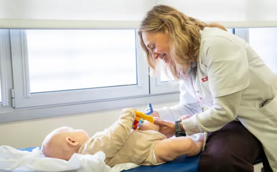 Terapia génica OTC en Sant Joan de Déu La Dra. Àngels García con un bebé en la consulta del Hospital Sant Joan de Déu